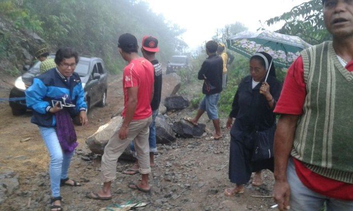 Beberapa suster dan para pejabat yang melintasi jalan menuju Elar terpaksa harus keluar dari mobil agar kendaraan mereka itu bisa melewati bagian jalan yang rusak parah