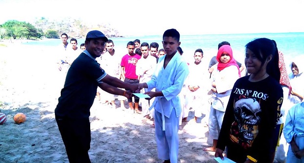 Ketua Perhimpunan Wartawan Manggarai Barat (PWMB) Sirilus Ladur menyerahkan Hadia Juara Satu Sepak Bola Pantai.