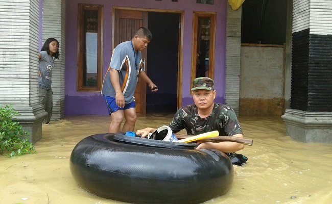 Seorang anggota TNI sedang membantu proses evakuasi korban banjir di Reo, Kecamatan Reok pada Minggu